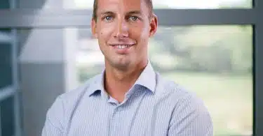 a man in a blue shirt standing in front of a window